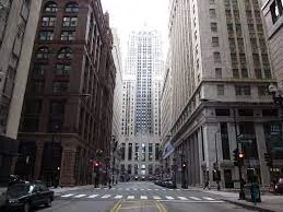 prédio da Bolsa de Chicago visto do chão, ladeado por outros prédios e se perdendo em um céu claro.
