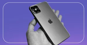 Ações da Apple representadas por uma mão segurando um Iphone em preto e branco sobre fundo roxo